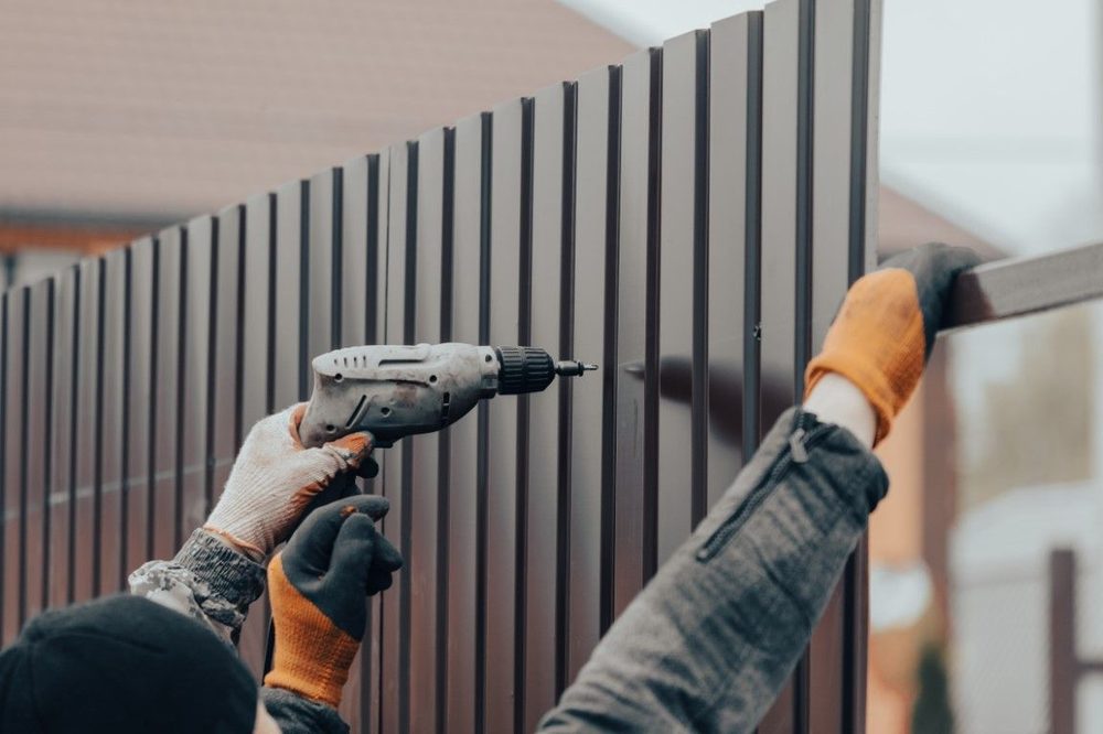 Installer securing an iron fence panel